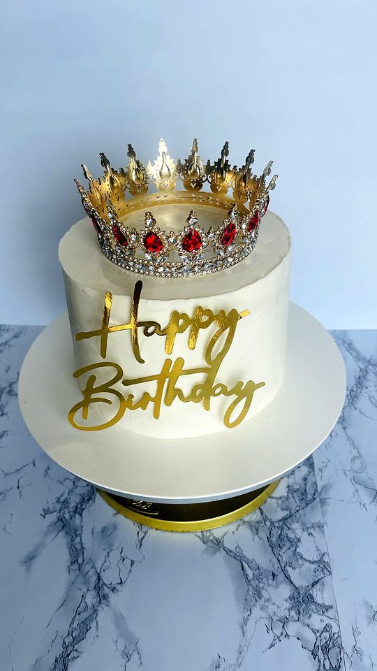White cake with golden crown and birthday sign in Playa del Carmen