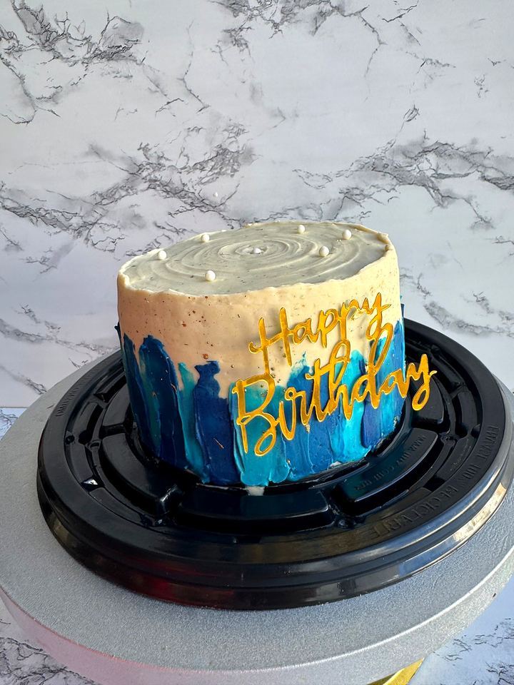 Cake with blue brushstrokes and gold birthday sign in Playa del Carmen